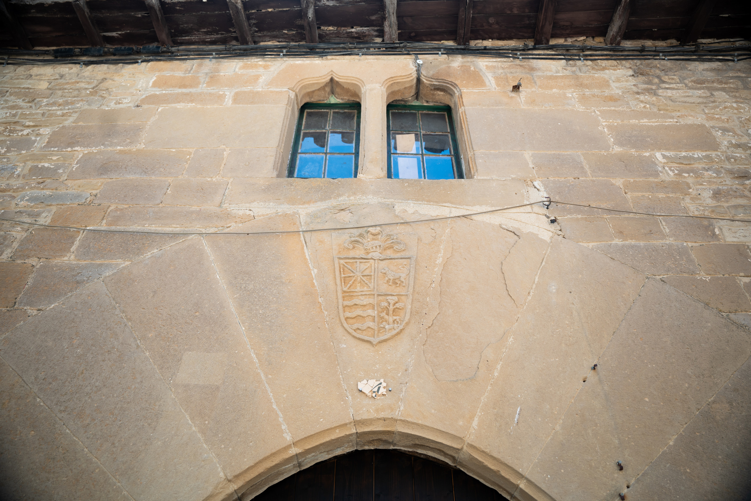 Escudo de armas y ventanas en la fachada de piedra de la casona